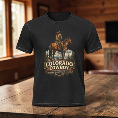 Cowboy T-shirt featuring a Colorado Rocky Mountain theme with a rugged cowboy silhouette, western lettering, and a distressed vintage outdoor aesthetic